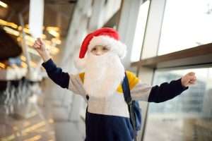 Little child wearing Santa Claus hat on background of an international airport