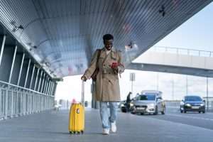A man at the airport with a yellow suitcase.