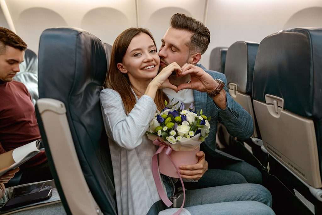 A happy couple in love showing the heart symbol in an Airplane.