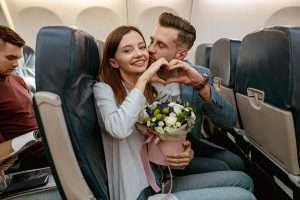 A happy couple in love showing the heart symbol in an Airplane.