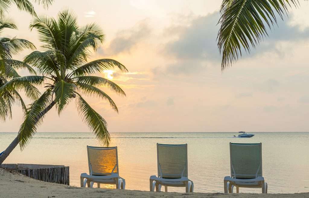 Sunrise on a beach with empty chairs on the sand