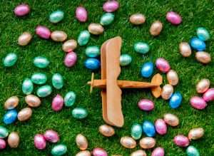 A wooden airplane surrounded by chocolate Easter eggs